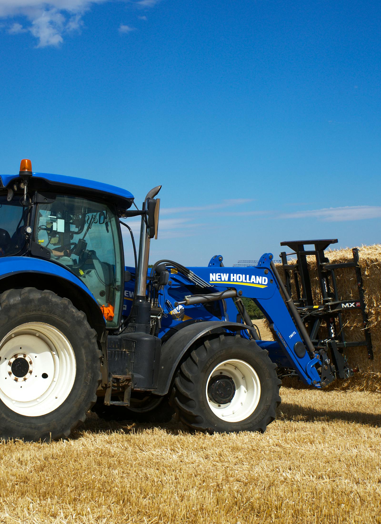 New Holland T-serie met balenklem in het veld.